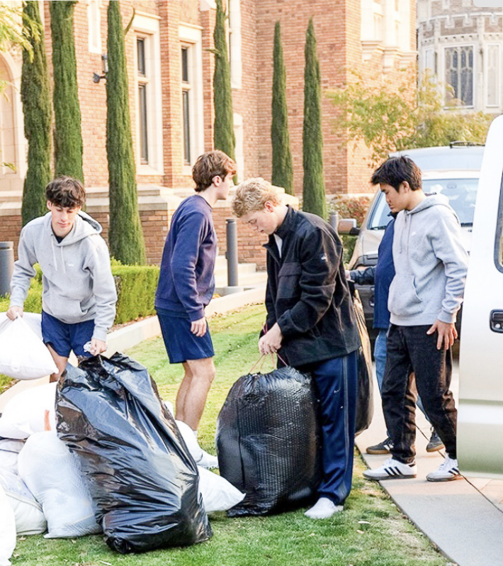 CUBS UNLOAD cars full of supplies in front of Caruso Hall